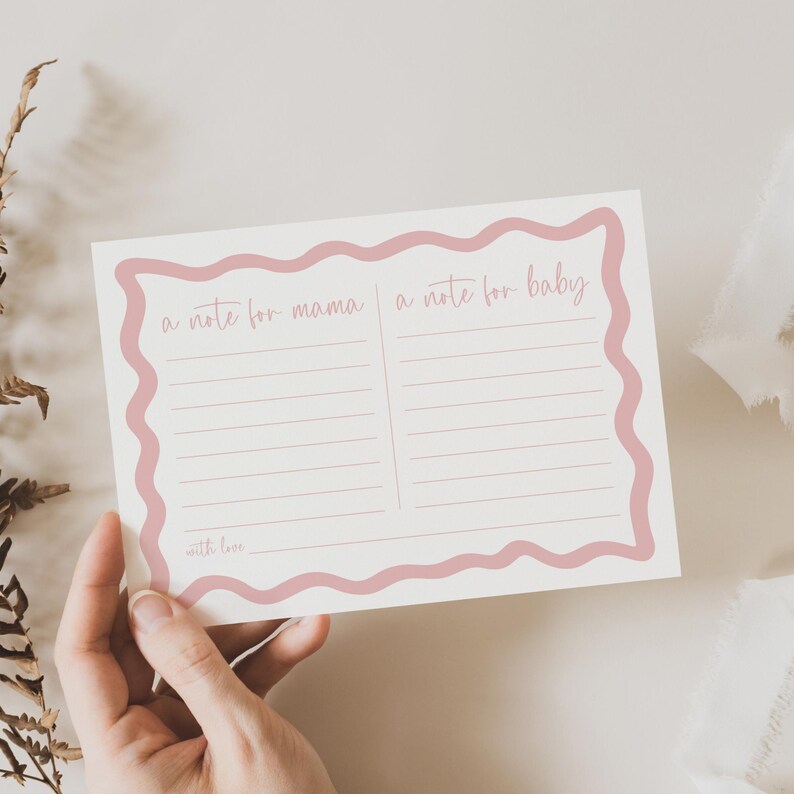 A hand holding a pink-bordered note card with blank lines for writing, placed on a white surface.