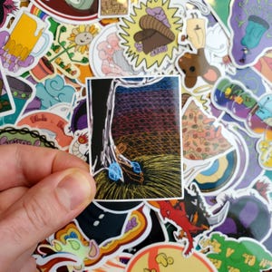 May include: A sticker featuring a colorful abstract design with a tree trunk and blue and yellow shapes. The sticker is on a background of other stickers.