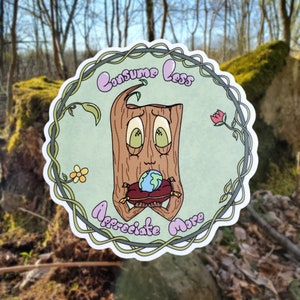 May include: A green and brown sticker featuring a cartoon tree holding a globe. The tree has a smiling face and the text "Consume Less Appreciate More" is written around the globe.