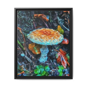 Peut inclure: Impression sur toile encadrée représentant une illustration de champignon coloré. Le champignon a un chapeau orange et blanc tacheté, une tige blanche et est entouré de feuilles aux tons orange, vert et marron. L'œuvre est sur fond sombre.