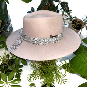 May include: A light pink felt fedora hat with a snakeskin patterned band and a small beaded accent.