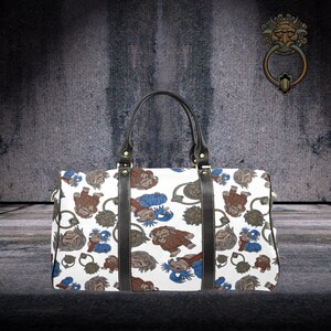 May include: White duffel bag with a repeating pattern of cartoon figures in brown, blue, and gray. The bag has black leather handles and trim. The background is a textured gray wall.
