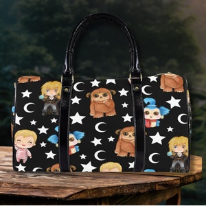 May include: Black leather travel bag with a whimsical design featuring cartoon characters and stars on a black background.