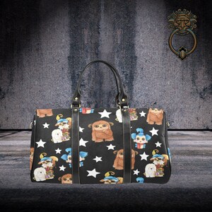 May include: A black travel bag with a white star pattern and colorful cartoon characters. The bag has two black leather handles and a zipper closure.