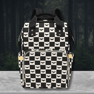 May include: Black and white checkered diaper bag with a bat pattern. The bag has a large main compartment and two smaller pockets on the sides.