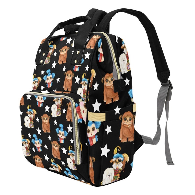 May include: A black diaper bag with a colorful print of cartoon characters. The bag has a large main compartment, two smaller pockets, and a zippered closure. The bag also has adjustable straps.