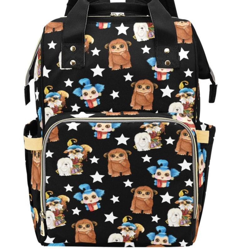 May include: A black diaper bag with a white star pattern and a cartoon character print. The bag has multiple pockets and a zipper closure.