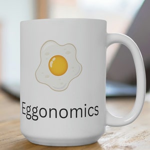 May include: White ceramic mug with a black and white illustration of a fried egg and the text "Eggonomics".