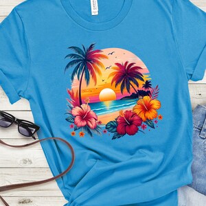 May include: A bright blue t-shirt with a colorful sunset scene featuring palm trees, flowers, and a beach. The design is centered on the shirt.