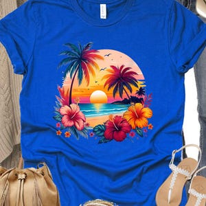 May include: A royal blue t-shirt with a colorful sunset scene featuring palm trees, a beach, and hibiscus flowers.