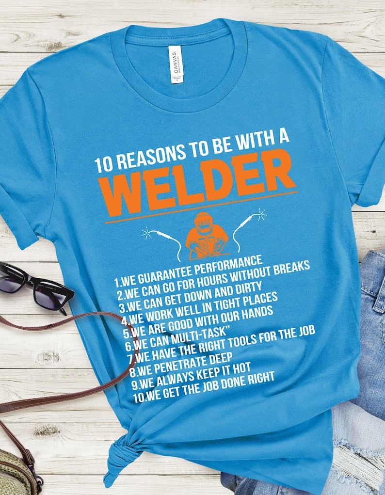May include: A turquoise t-shirt with the text "10 REASONS TO BE WITH A WELDER" in white and orange. The shirt features a graphic of a welder and a list of reasons. Sunglasses and a purse are visible.