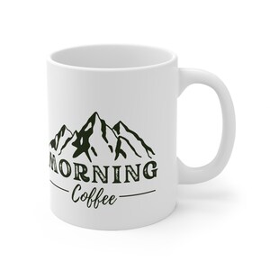 Può includere: Tazza da caffè in ceramica bianca con una grafica di montagne nere e verdi e il testo "Morning Coffee".