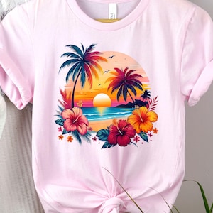 May include: Pink t-shirt with a graphic of a tropical sunset scene with palm trees, a beach, and hibiscus flowers.