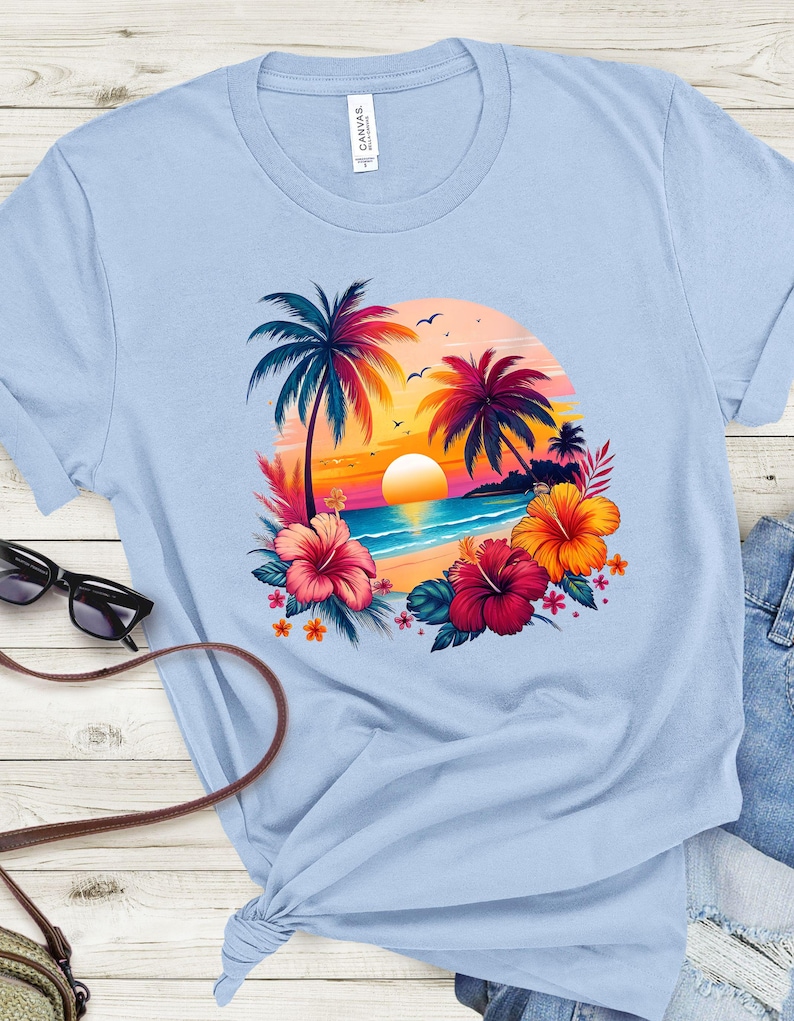 May include: Light blue t-shirt with a colorful graphic of palm trees, a sunset, and hibiscus flowers on a beach.