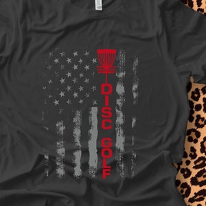 May include: A dark gray t-shirt with a distressed American flag design and the words "DISC GOLF" in red.