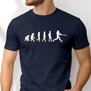 Op de afbeelding: Marineblauw T-shirt met een witte afbeelding van de evolutie van honkbal. Het ontwerp toont een progressie van aap naar honkbalspeler. Het shirt is gemaakt van een zacht materiaal en heeft korte mouwen.