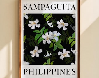 May include: A framed wall art print featuring a black background with white Sampaguita flowers and green leaves. The text SAMPAGUITA is printed in black at the top, and the word PHILIPPINES is printed in black at the bottom of the white border.