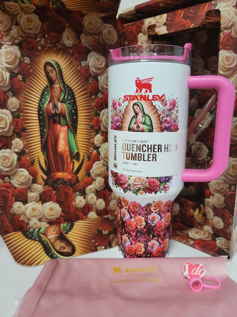 May include: A white 40 oz Stanley Flowstate Quencher H2.0 tumbler with a pink handle and lid. The tumbler features a graphic of the Virgin of Guadalupe surrounded by roses, with a floral pattern at the base. It includes a pink heart-shaped straw topper.