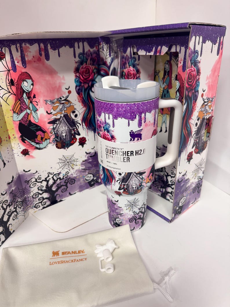 May include: A Stanley Quencher H2.0 tumbler featuring a Nightmare Before Christmas theme with purple glitter drip, floral patterns, and character illustrations. The tumbler includes a white handle, a lid, and a branded dust bag with white accessories.
