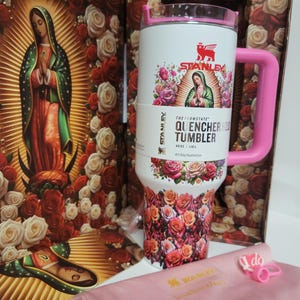 May include: A white 40 oz Stanley Flowstate Quencher H2O tumbler featuring a graphic of Our Lady of Guadalupe surrounded by roses, a pink handle, and a pink lid. The tumbler is displayed with a matching floral box and a pink fabric accessory.