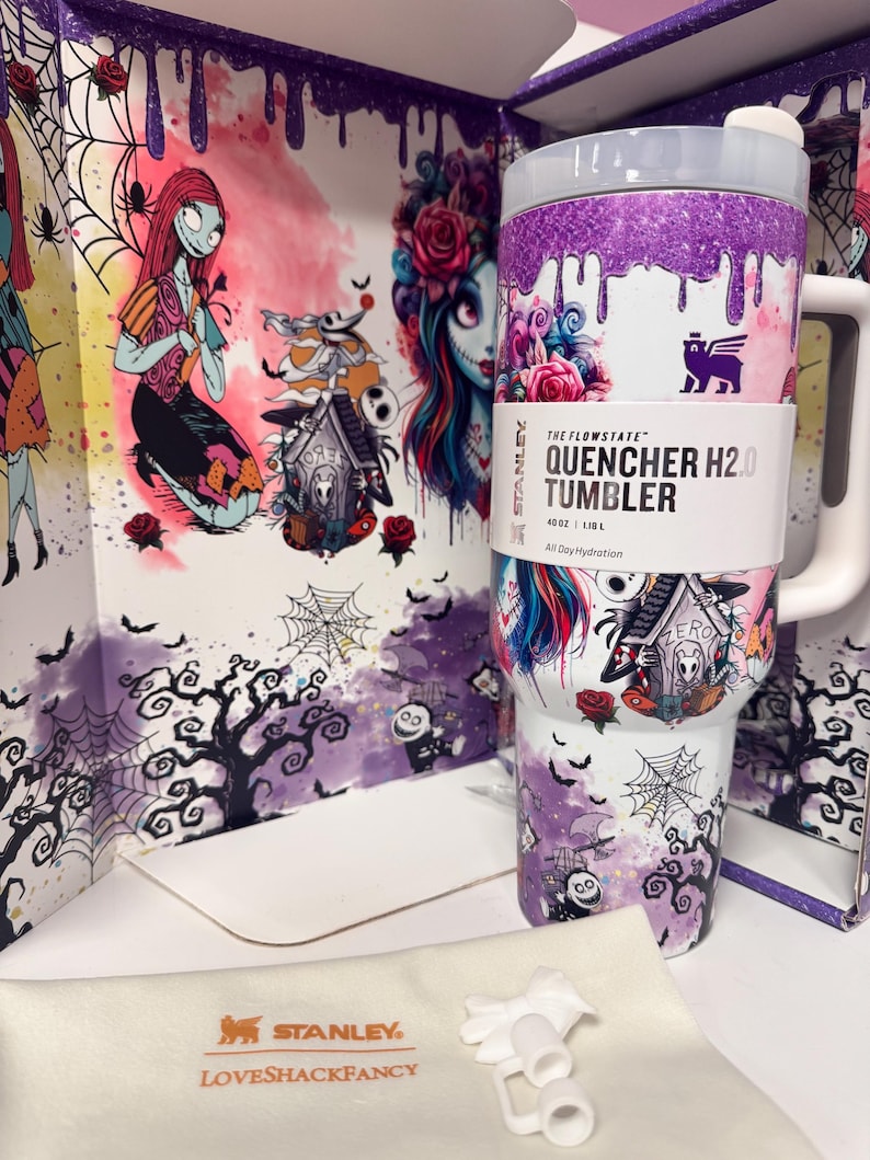 May include: A white Stanley Flowstate Quencher H2.0 tumbler with a 40oz capacity, featuring a purple glitter drip design at the top and a Nightmare Before Christmas graphic print. It includes a white handle, a lid, and a separate white straw attachment.