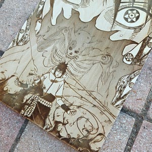 May include: A wood-burned artwork featuring a manga-style illustration of a character with detailed eyes and a dynamic action pose. The artwork is in shades of brown and tan, with intricate line work.