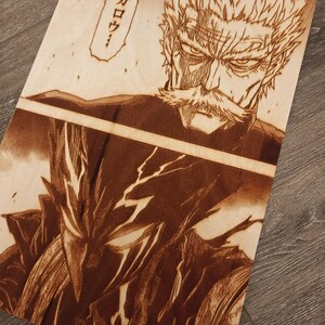 May include: Wood-burned artwork featuring two characters from a manga. The top character has a stern expression and a large mustache. The bottom character has a detailed, armored appearance. Japanese text is in a speech bubble.