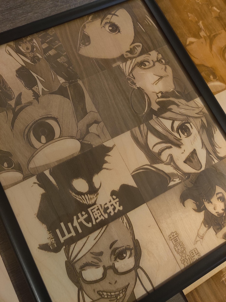 May include: A framed wood panel featuring engraved anime-style illustrations. The artwork includes various characters with expressive faces and Japanese text. The frame is black, and the wood has a natural, light brown color.