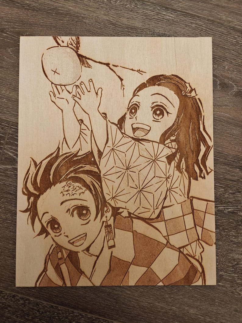 May include: A wood-burned artwork featuring two anime characters. One character is holding up their hands towards a round object. The other character is smiling. The artwork is on a light-colored wooden surface.