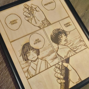 May include: Framed wooden artwork featuring a manga comic strip. The artwork is laser-etched with four panels, showcasing characters and speech bubbles with text. The frame is black.