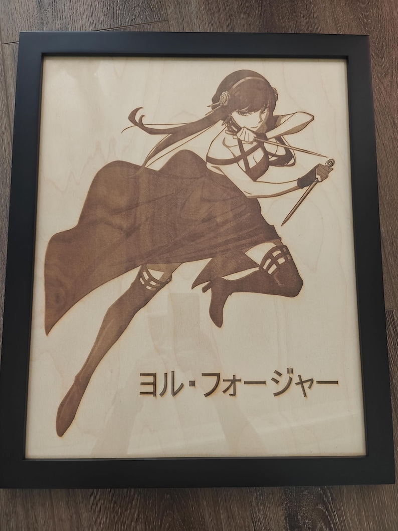 May include: Wooden framed artwork featuring a detailed laser-etched illustration of a female anime character in a dynamic pose. The artwork is in shades of brown and tan, with Japanese text at the bottom. The frame is black.