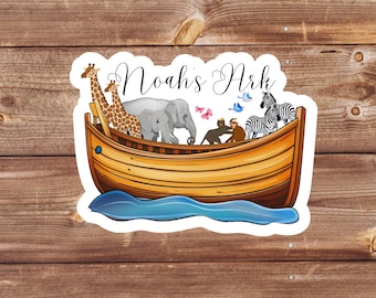 May include: A sticker featuring a cartoon illustration of Noah's Ark with animals on board. The ark is brown and yellow with a blue wave underneath. The text "Noah's Ark" is written in cursive above the ark.