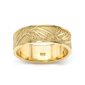 May include: A gold band with a textured design of a tree branch. The band is marked with "12K" on the inside.