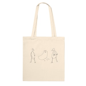 Può includere: Borsa tote color crema con tre illustrazioni di uccelli stravaganti in nero. Gli uccelli sono disegnati con linee semplici, conferendo loro un aspetto giocoso. La borsa ha manici lunghi per essere portata a spalla.