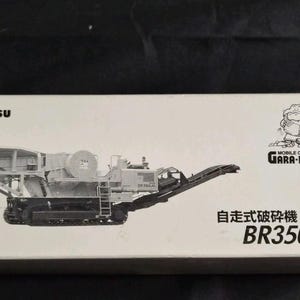 Op de afbeelding: Witte doos met een illustratie van een Komatsu mobiele crusher model. De doos bevat Japanse en Engelse tekst, waaronder "BR350JG" en "Gara-Pagos". De afbeelding toont een gedetailleerde tekening van de machine.
