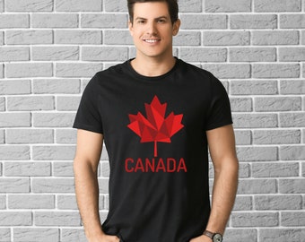 Pode incluir: Uma camiseta preta com um design de folha de bordo geométrica vermelha e a palavra "CANADA" impressa abaixo.