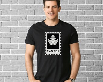 Pode incluir: Uma camiseta preta com um gráfico branco de uma folha de bordo dentro de um selo postal com a palavra "CANADA" abaixo.