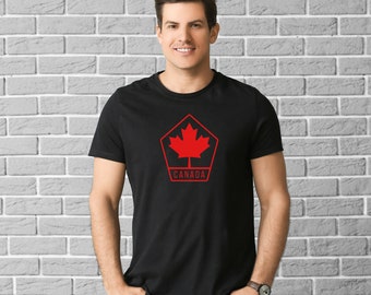 Pode incluir: Uma camiseta preta com uma folha de bordo canadense vermelha em forma de pentágono e a palavra "CANADA" abaixo.