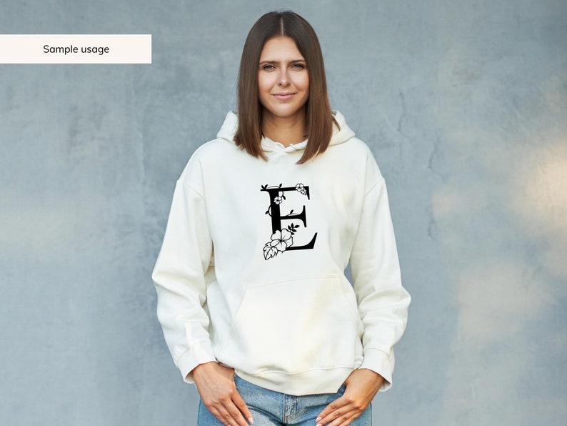 May include: A white hoodie with a black floral design featuring the letter "E" on the front.