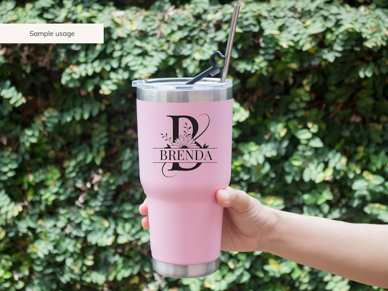May include: A pink stainless steel tumbler with a black floral monogram design featuring the letter "B" and the name "BRENDA".
