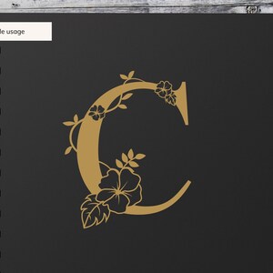 May include: A gold letter C with floral embellishments. The letter is on a black background.