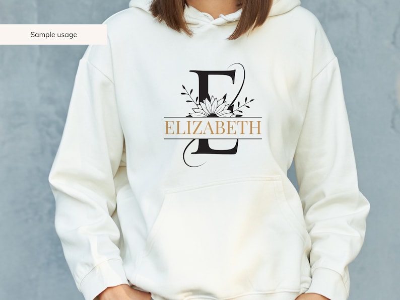 May include: White hoodie with a black floral design and the name "ELIZABETH" printed in gold.