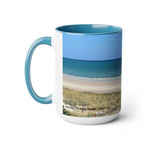 This Beach View Coffee Mug is a great way to start your day with a relaxing and refreshing scene of a sailboat on the ocean.