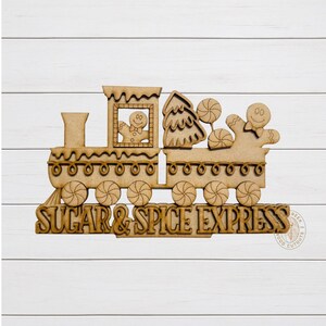 May include: Wooden cutout of a train with gingerbread men, a Christmas tree, and lollipops. The text "SUGAR & SPICE EXPRESS" is carved into the wood. The train has decorative wheels and a chimney.