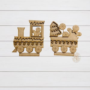 May include: Two wooden Christmas train cutouts. The train engine features a gingerbread man in the window. The second car has a Christmas tree and gingerbread men with lollipops. The wheels are circular with a spiral design.