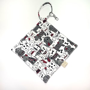May include: White fabric pouch with a black and white dog pattern. The pouch has a red accent and a black ring with a silver key chain.