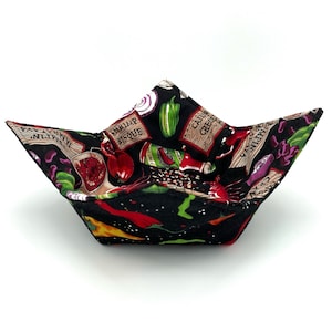 May include: Black fabric bowl with a colorful print of peppers, spices, and the words "Shrimp Bisque" and "Cajun Creole".