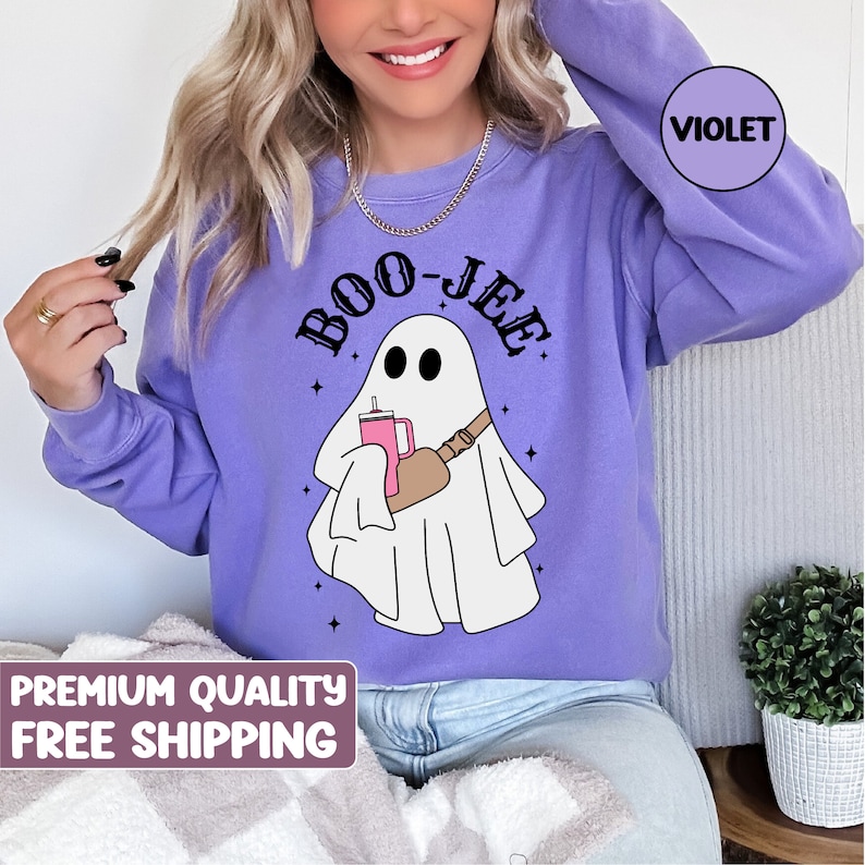 May include: Purple sweatshirt featuring a white ghost holding a pink drink and the text "BOO-JEE" in black.