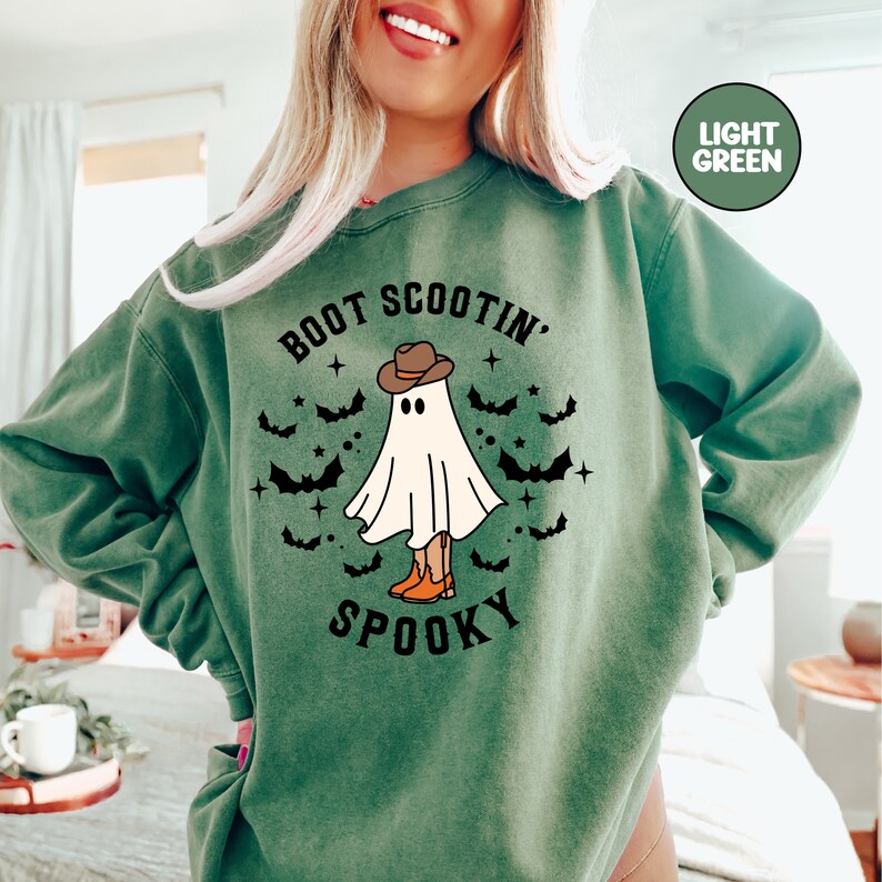 May include: A light green sweatshirt with the text "Boot Scootin' Spooky" and a ghost wearing a cowboy hat and boots.
