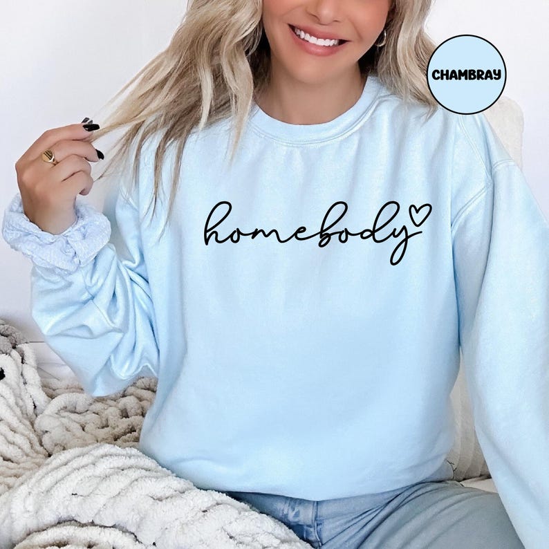 May include: A light blue sweatshirt with the text "homebody" in black cursive lettering and a small heart symbol.
